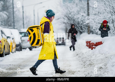 Mosca, Russia - 13 febbraio 2019: la ragazza dalla consegna del cibo Yandex servizio.Il cibo va sulla coperta di neve di Mosca. Foto Stock