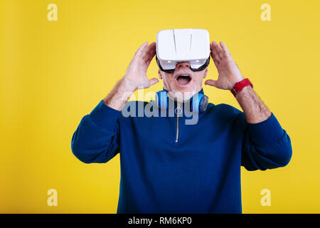 Grigio-dai capelli uomo pensionato sentirsi spaventati indossando occhiali VR Foto Stock