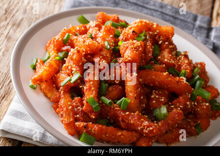 Asian miele peperoncino Spicchi di patate a caldo con salsa dolce di sesamo e le cipolle verdi close-up su una piastra orizzontale. Foto Stock