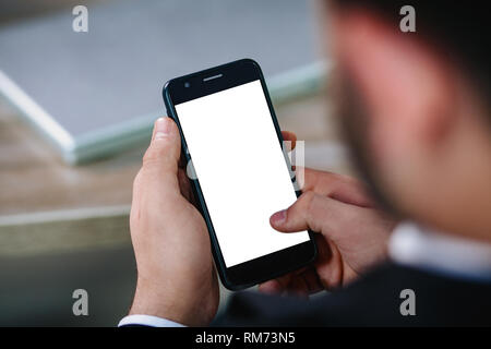 Mano d'uomo tenendo lo smartphone con il bianco schermo vuoto Foto Stock