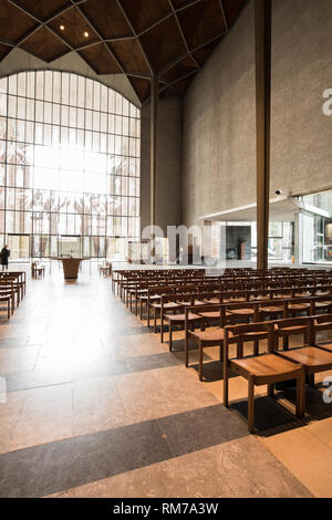 Navata centrale con sedie a Coventry Cathedral, Inghilterra, guardando verso la estremità sud e la finestra di vetro con incisioni di angeli da th eartist John Hutton. Foto Stock