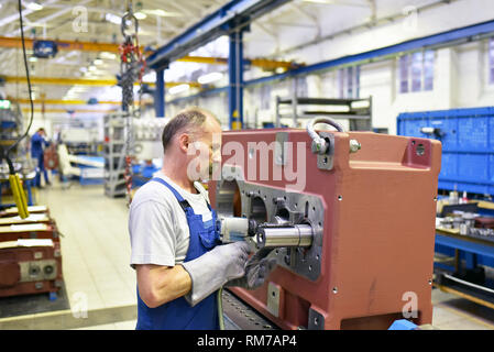 Lavoratore anziano in ingegneria meccanica - fabbrica industriale per la produzione di scatole ingranaggi in acciaio Foto Stock