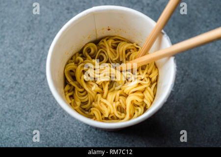 Istantaneo aromatizzato al Curry spaghetti ramen servito con bacchette. in una tazza di plastica. Tradizionale Fast Food. Foto Stock