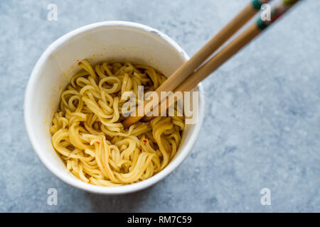 Istantaneo aromatizzato al Curry spaghetti ramen servito con bacchette. in una tazza di plastica. Tradizionale Fast Food. Foto Stock