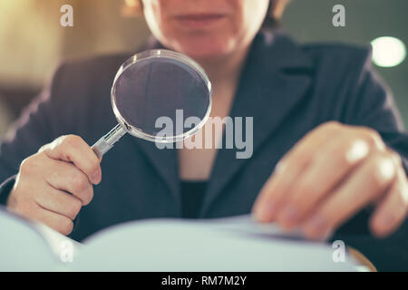 Attività di audit di corruzione il concetto di ispezione, ispettore femmina con lente di ingrandimento Foto Stock