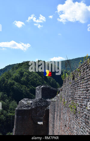 Bandiera rumena sventolare nel vento presso la rovina del castello di Poenari. La Romania bandiera nazionale. Foto Stock