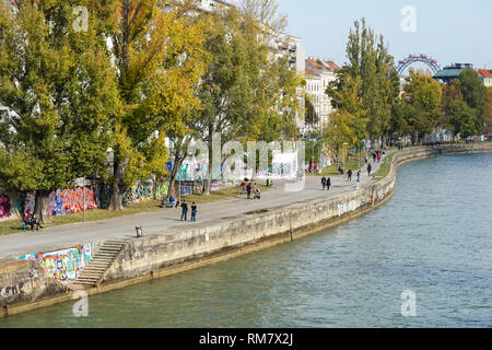 Le persone che si godono la soleggiata clima autunnale presso la banca di Donaukanal (Canale del Danubio) a Vienna, in Austria Foto Stock