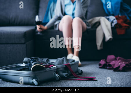 Vista ritagliata della donna seduta con un bicchiere di vino rosso mentre il confezionamento in soggiorno dopo la rottura con il fidanzato Foto Stock