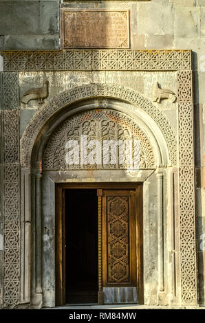 Aprire lo sportello di legno coperto con un scolpito ornamento etnico, e una pietra ovale con piano intagliato modelli di frutta al di sopra della porta chiesa di Katoghike in th Foto Stock