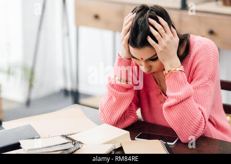 Stanco studente indiano con mal di testa guardando i notebook a casa Foto Stock