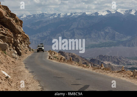 Mountain bike la corsia di una strada sterrata avvolgimento oltre i robusti e montagne brulle della Khardungla Pass in Tibet Foto Stock