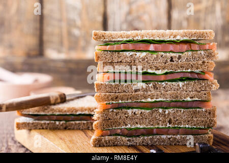 Sana sandwich vegetariano con salmone affumicato e verdi. Brindisi sulla scheda di taglio su legno rustico sfondo, vicino il fuoco selettivo Foto Stock