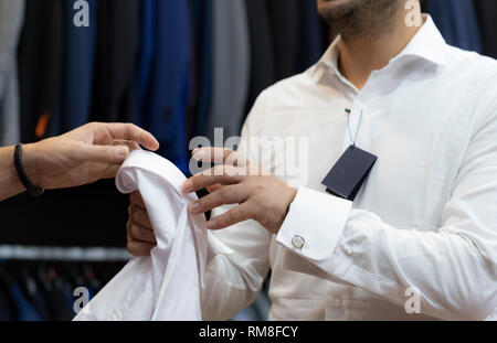 Sarto offrendo la camicia bianca a un cliente Foto Stock