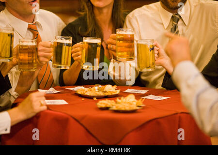 Happy business persone che allevano i bicchieri in un brindisi seduti a un tavolo in un ristorante. Foto Stock