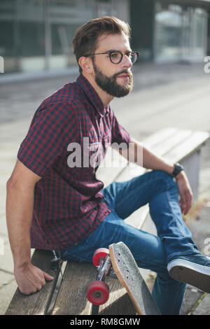 Skater barbuto seduto su un banco di lavoro Foto Stock