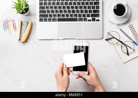 Una donna sta facendo un acquisto online, mock up e della carta di credito cellulare mobile sulla scrivania in ufficio isolato in modo bello sfondo marmo, copia spac Foto Stock
