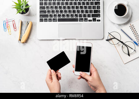 Una donna sta facendo un acquisto online, mock up e della carta di credito cellulare mobile sulla scrivania in ufficio isolato in modo bello sfondo marmo, copia spac Foto Stock