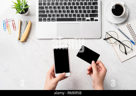 Una donna sta facendo un acquisto online, mock up e della carta di credito cellulare mobile sulla scrivania in ufficio isolato in modo bello sfondo marmo, copia spac Foto Stock