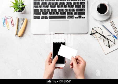 Una donna sta facendo un acquisto online, mock up e della carta di credito cellulare mobile sulla scrivania in ufficio isolato in modo bello sfondo marmo, copia spac Foto Stock