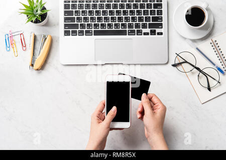 Una donna sta facendo un acquisto online, mock up e della carta di credito cellulare mobile sulla scrivania in ufficio isolato in modo bello sfondo marmo, copia spac Foto Stock