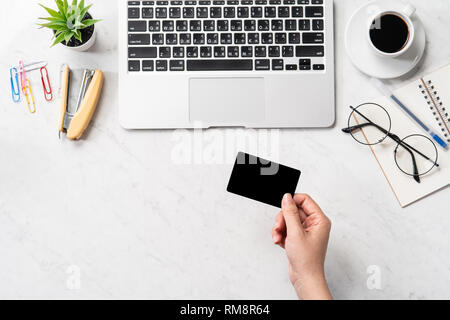 Una donna sta facendo un acquisto online, mock up e della carta di credito cellulare mobile sulla scrivania in ufficio isolato in modo bello sfondo marmo, copia spac Foto Stock