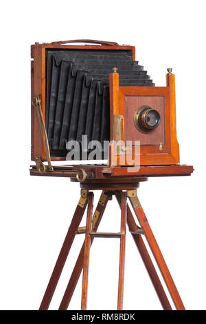 Un antico fotocamera a soffietto sulla cima di un vecchio cavalletto di legno isolato su bianco Foto Stock