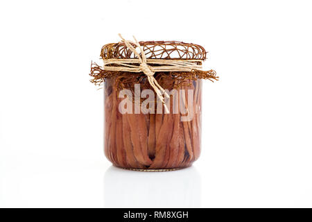 Fatte a mano i filetti di acciuga in olio di oliva in modo trasparente il vasetto di vetro. Il vaso pieno di salato di filetti di acciughe isolati su sfondo bianco, vicino. Foto Stock