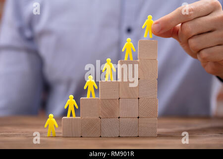 Close-up di giallo figure umane che conduce sulla parte superiore dei blocchi di legno in ufficio Foto Stock