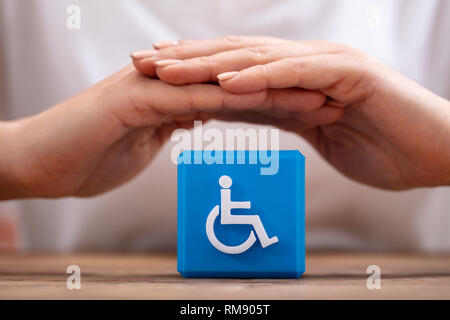 Close-up di una donna di mano la protezione blu blocco cubico con icona disabilitata Foto Stock