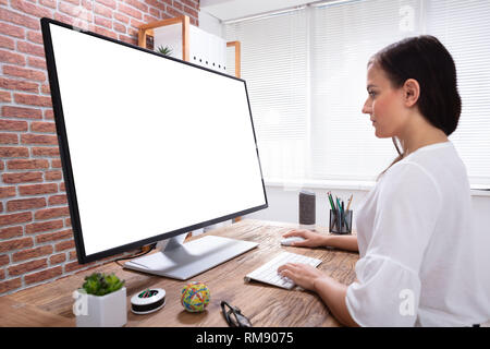 Close-up di una imprenditrice Guardando bianco sullo schermo del computer sulla scrivania in legno Foto Stock