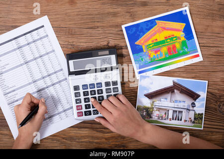 Close-up di una persona il calcolo della perdita di calore e l'efficienza energetica di una casa Foto Stock