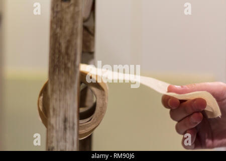Mano tenendo la carta igienica dal porta bobina Foto Stock