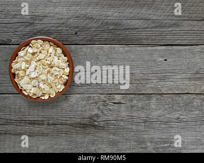 Di fiocchi di cereali in marrone della piastra sulla tabella di schede di grigio. Foto Stock