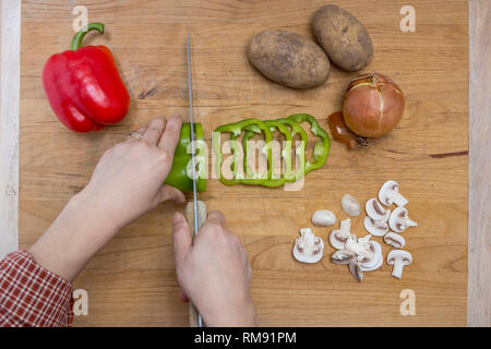 L atto di taglio di un assortimento di verdure su un tagliere. Foto Stock