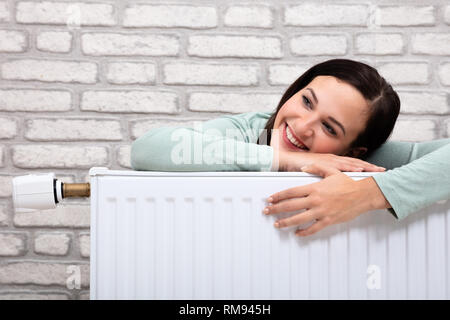 Ritratto di un felice giovane donna appoggiata sul radiatore di riscaldamento Foto Stock