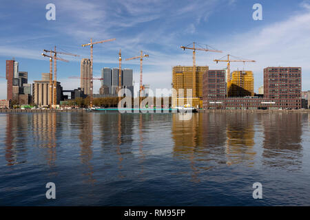 Skyline della città con edifici in corrispondenza di un fronte fiume in habited mediante gru nella città olandese di Rotterdam Foto Stock