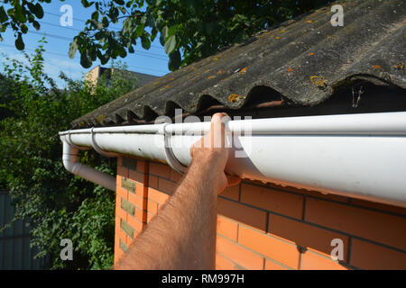 Copritetti di riparazione e di rinnovamento di gronda del tetto sulla vecchia casa di mattoni tetto in amianto. Foto Stock