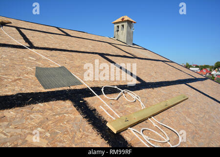 Preparazione di coperture scandole di asfalto di installazione su casa costruzione tetto in legno con spruzzatura di bitume e la protezione di corda, kit di sicurezza. Cost per tetti Foto Stock