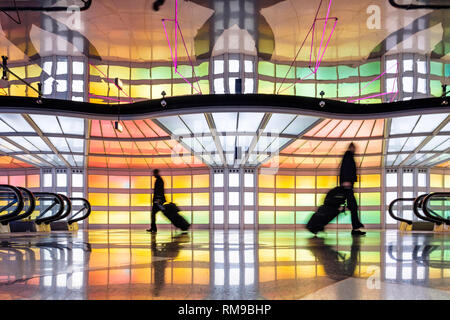 I passeggeri del trasporto aereo, business la gente camminare e colorati di luci al neon installazione d arte da Michael Hayden, tunnel pedonale, Chicago O'Hare Airport Terminal. Foto Stock