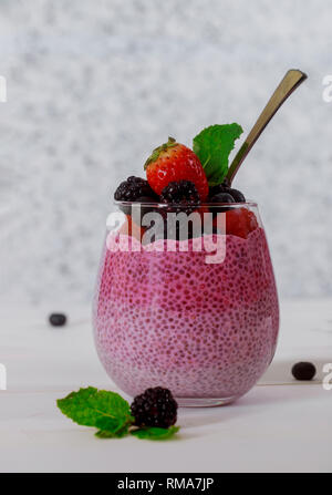 Una sana vari dessert prima colazione con fragole, chia semi pudding con mirtilli in un bicchiere Foto Stock