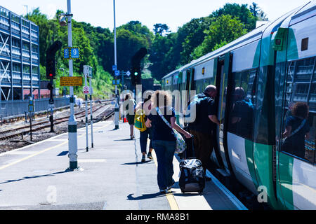 BIRMINGHAM, Regno Unito - Marzo 2018 pendolari sulla piattaforma di salire a bordo di un treno. L'uomo entra in un carro ferroviario. Passeggeri a piedi verso il carrello sulla giornata di sole Foto Stock