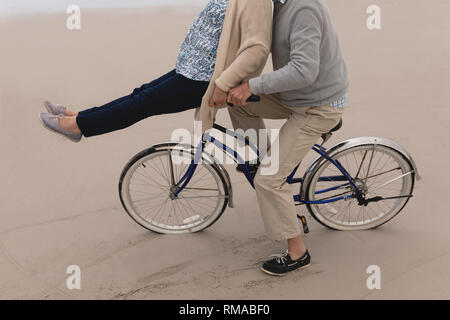 Senior con uomo donna senior Bicicletta Equitazione sulla spiaggia Foto Stock