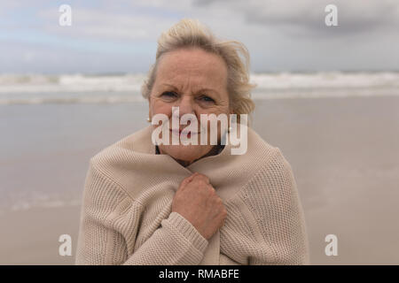 Active senior donna avvolta in un ponticello sulla spiaggia Foto Stock