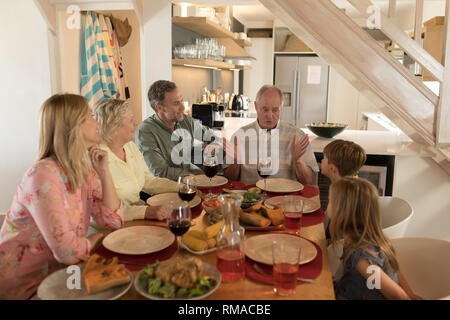 Famiglia interagire gli uni con gli altri mentre avente pasto sul tavolo da pranzo Foto Stock