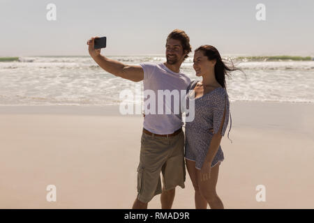 Romantico lieto coppia giovane tenendo selfie con telefono cellulare sulla spiaggia Foto Stock