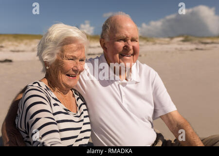 Felice coppia senior seduto sulla spiaggia Foto Stock