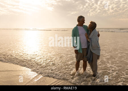 Coppia senior che abbraccia ogni altro sulla spiaggia Foto Stock