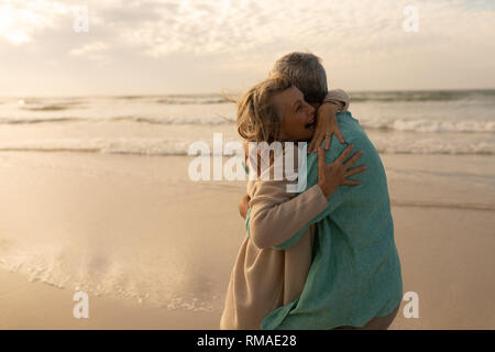 Attivo coppia senior che abbraccia ogni altro sulla spiaggia Foto Stock