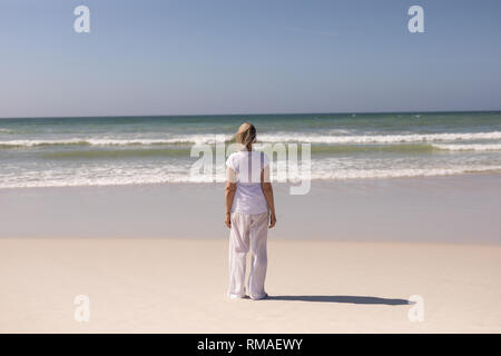 Vista posteriore del senior donna in piedi sulla spiaggia Foto Stock