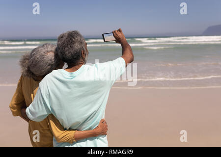 Coppia senior tenendo selfie con telefono cellulare sulla spiaggia Foto Stock